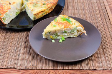 Bambu masasındaki güveçte güveçte yeşil fasulye, karnabahar ve brokoliden oluşan kahverengi tabakta güveç var.