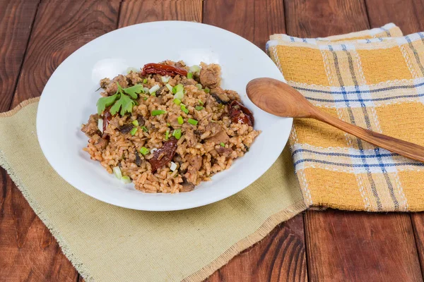 Paella Cozida Com Carne Cogumelos Prato Branco Com Colher Madeira — Fotografia de Stock