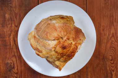 Büyük bir parça domuz omzu eski kırsal masada beyaz tabağın üzerinde, üst manzara