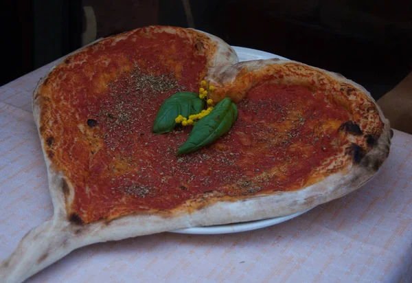 Pizza com molho de tomate e manjericão na forma de um tipo de coração — Fotografia de Stock