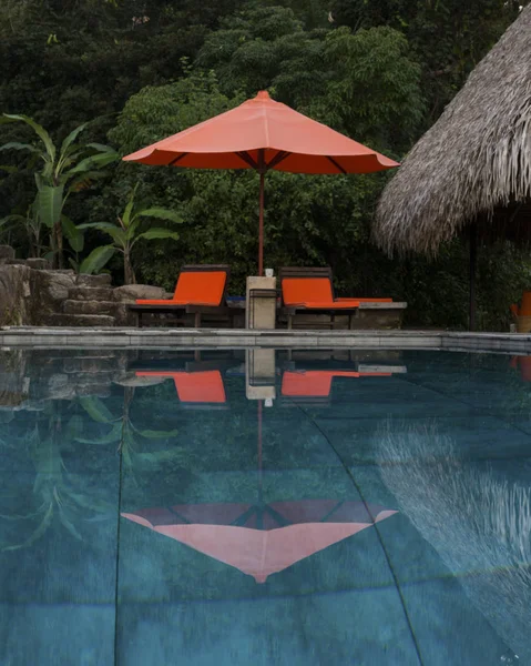 Chaise loungers and patio umbrella at poolside in resort, Yelapa, Jalisco, Mexico