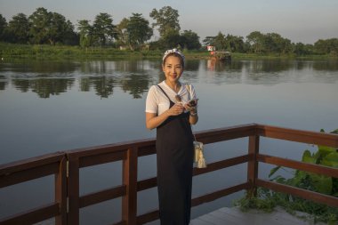 Happy woman standing at lakeside, Chiang Rai, Thailand clipart
