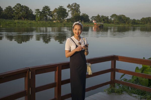 Happy woman standing at lakeside, Chiang Rai, Thailand