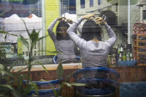 Вид сзади на женщину, расчесывающую волосы, Луанг Прабанг, Лаос
