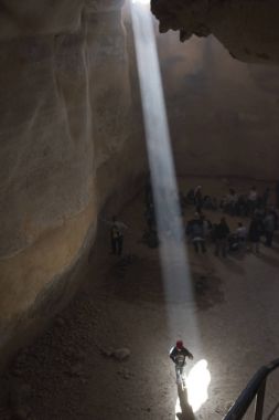Kişi üzerinde mağarada, Masada, Judean Desert, Dead Sea Region, İsrail ayakta düşen güneş ışığı