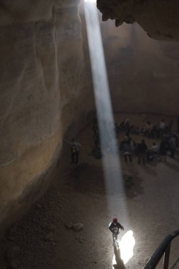 Kişi üzerinde mağarada, Masada, Judean Desert, Dead Sea Region, İsrail ayakta düşen güneş ışığı