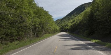 Empty road amidst trees by hills, Petit Etang, Cape Breton Highlands National Park, Cape Breton Island, Nova Scotia, Canada clipart