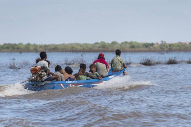 Tonle Sap Gölü, Kampong Phluk, Siem Reap, Kamboçya'da hareketli bir motorlu tekne oturan insanlar