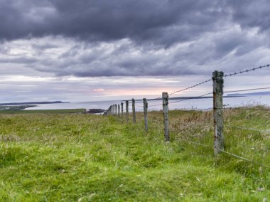 Fence on landscape at coast against cloudy sky, John o' Groats, Caithness, Scottish Highlands, Scotland clipart