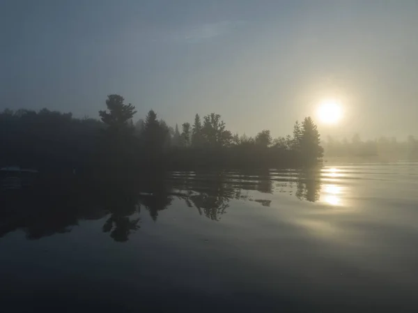 Reflection of trees in the lake at dusk, Lake of The Woods, Ontario, Canada