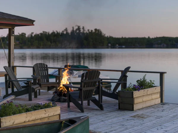 Adirondack chairs and campfire on a dock, Lake of The Woods, Ontario, Canada
