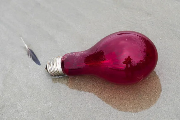 Close-up of a red light bulb on sand, Pacific Rim National Park Reserve, British Columbia, Canada