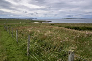 Fence at coast against cloudy sky, John o' Groats, Caithness, Scottish Highlands, Scotland clipart