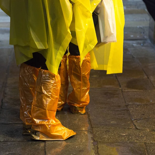 Low section of people wearing plastic raincoat standing in rain, San Polo, Venice, Veneto, Italy