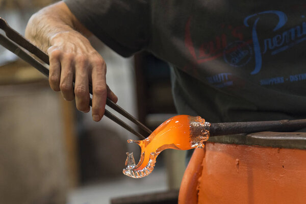 Man working with molten glass using a tweezers in glass factory, Murano, Venice, Veneto, Italy