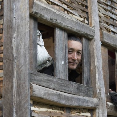 Adam ahşap evin penceresinden, Punakha, Bhutan arıyor