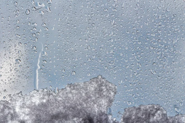 A horizontal texture of water droplets and melting snow and ice is on the glass and on a background of blue sky — Stock Photo, Image