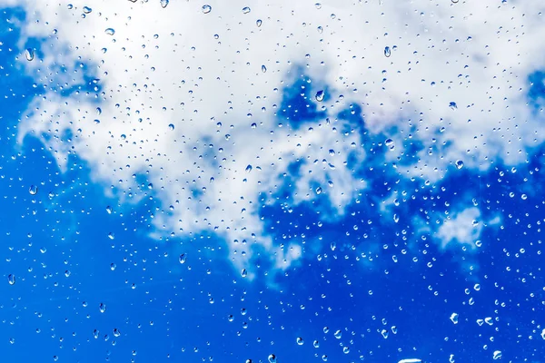 A horizontal texture of water droplets is on the glass and on a background of blue sky