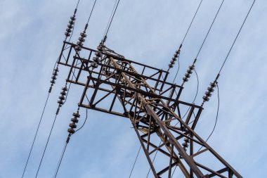 Paslı elektrik hattı mavi gökyüzü arka planında.