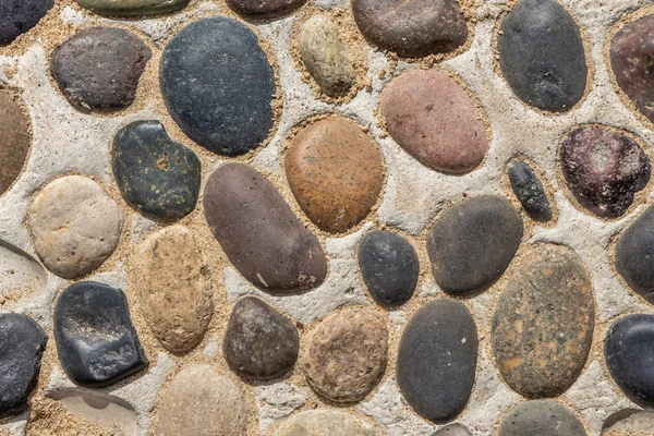 Красивая текстура дорожки из серых и цветных гладких камней на желтом фоне с песком в парке — стоковое фото