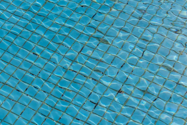 小さな正方形のセラミックタイルの質感の青の背景にプール内の太陽光と水の美しい質感 — ストック写真