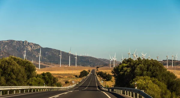 Large group of white wind generators produces alternative energy by wind on the fields in Europe in Spain on the both side of a road with cars — Stock Photo, Image