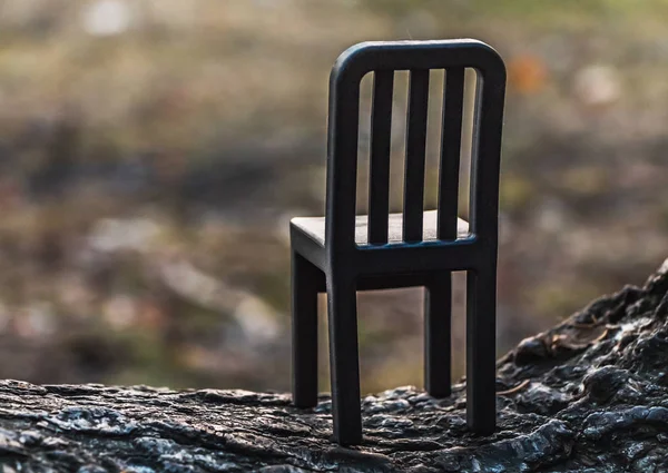 Hermoso juguete pequeño silla de plástico negro está sobre un fondo borroso en el parque —  Fotos de Stock