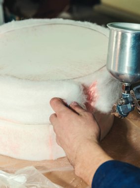 Döşeme mobilyası yapmak, bar taburesi için koltuk hazırlamak, sprey tabancayla yapıştırıcı sürmek.