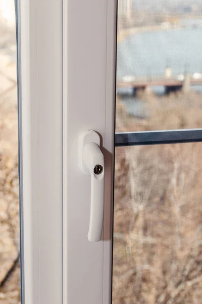 A handle with a lock on a window frame, a key-locked window, a safety tool for children close-up