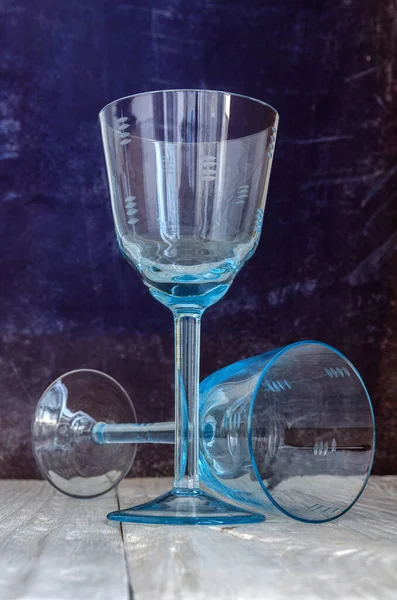 Two old glasses of blue glass on a wooden background, close up