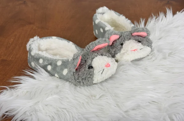 Fuzzy bunny slippers on white fur rug — Stockfoto
