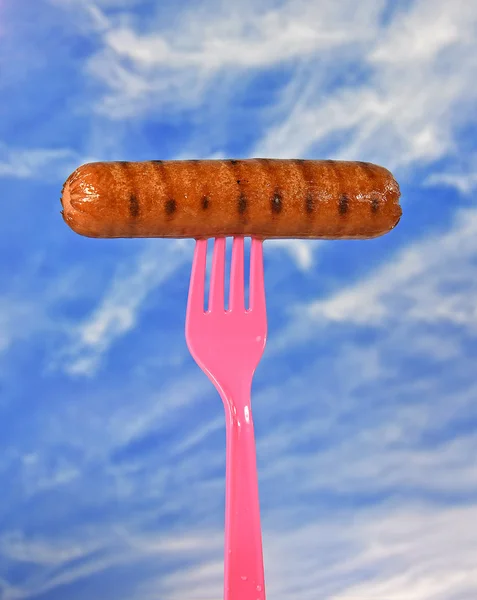 Grilled hot dog on plastic fork — Stock Photo, Image