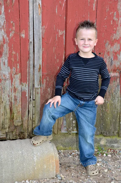 Smiling boy by red barn — Stock Photo, Image