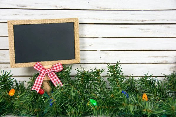 Black chalkboard with bow in Christmas pine — Stock Photo, Image