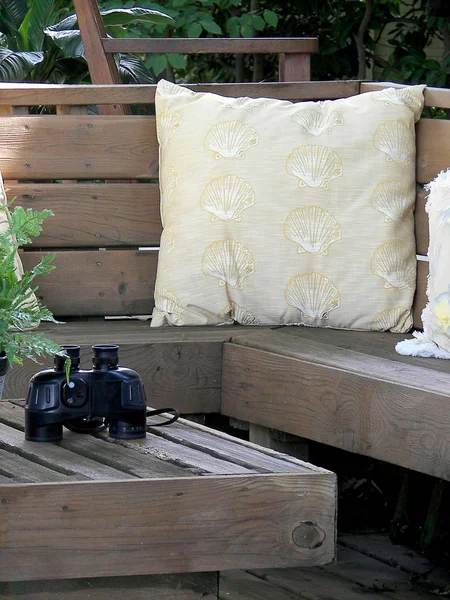 Подушка из ракушки и бинокль на палубе — стоковое фото