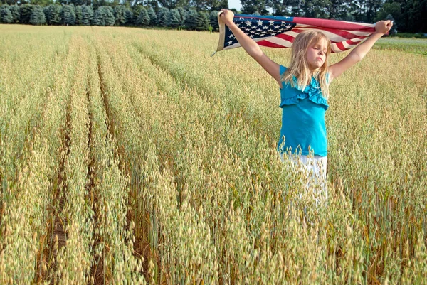 Νεαρό κορίτσι στο πεδίο σιτάρι με σημαία — Φωτογραφία Αρχείου