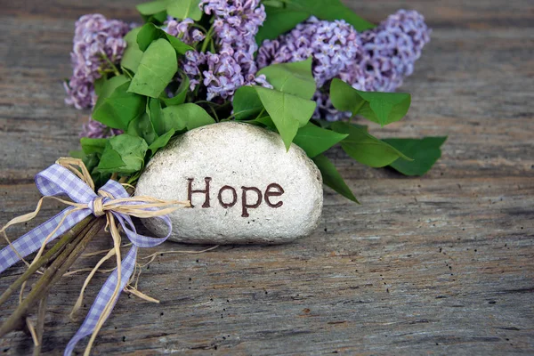 Word hope carved in stone with lilacs — Stock Photo, Image