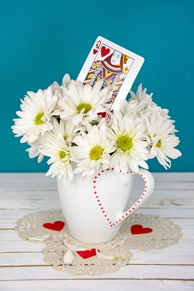Queen of hearts and daisies in white cup — Stock Photo, Image