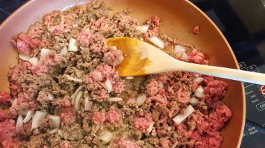 beef hamburger and onions cooking in pan clipart