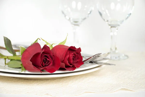 Rosas rojas y cubiertos en el plato de la cena —  Fotos de Stock