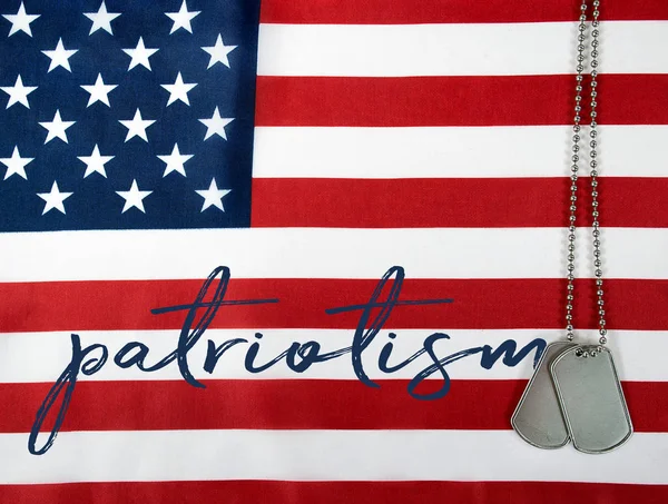 Word patriotism and dog tags on flag — Stock Photo, Image