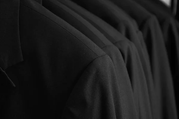 Row of black dinner jackets in closet — Stock Photo, Image