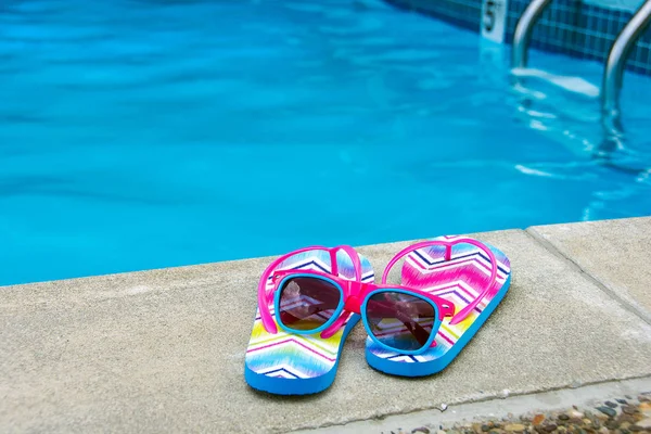 Óculos de sol e chinelos à beira da piscina — Fotografia de Stock