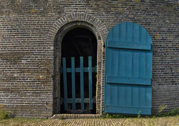 Μπλε ξύλινη πόρτα στον εξωτερικό τοίχο από τούβλα — Φωτογραφία Αρχείου