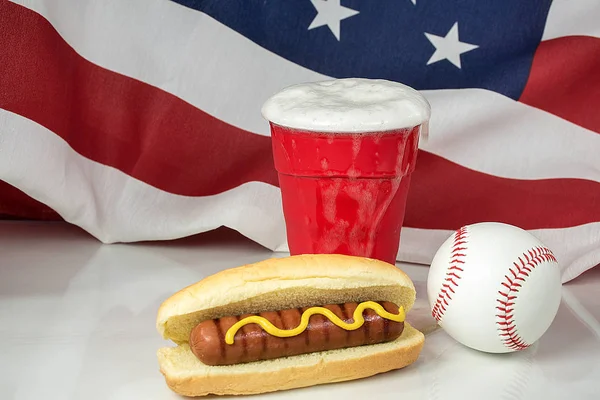 赤カップとホットドッグとアメリカ国旗背景と野球にビールにあふれて — ストック写真