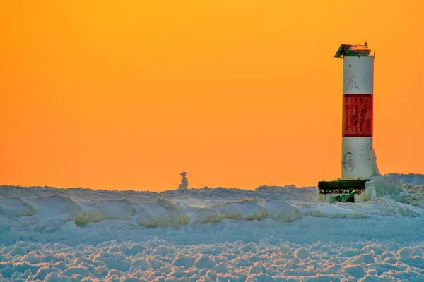 冰冻的冬季码头上有红白相间的灯塔 — 图库照片
