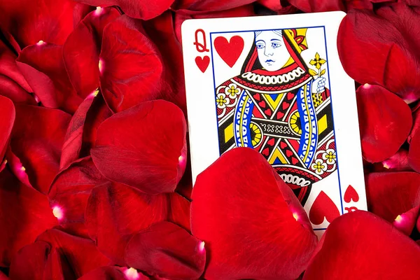 close up of queen of hearts card in red rose petals