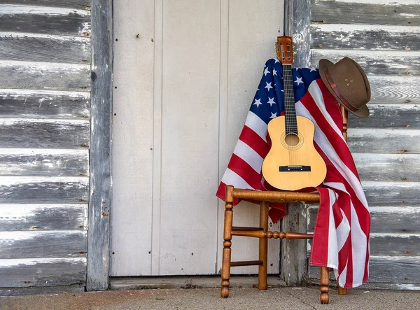 木製のドアで風化茶色の帽子とアメリカの国旗と木製の椅子に 弦ギター — ストック写真