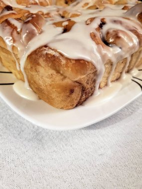 Ev yapımı tarçınlı ruloları beyaz kare tabakta serpiştirin.