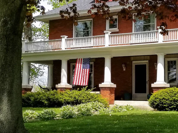 American flag hanging on house front porch with white columns